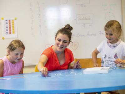 Schüler rechnen am Tisch mit Lehrerin